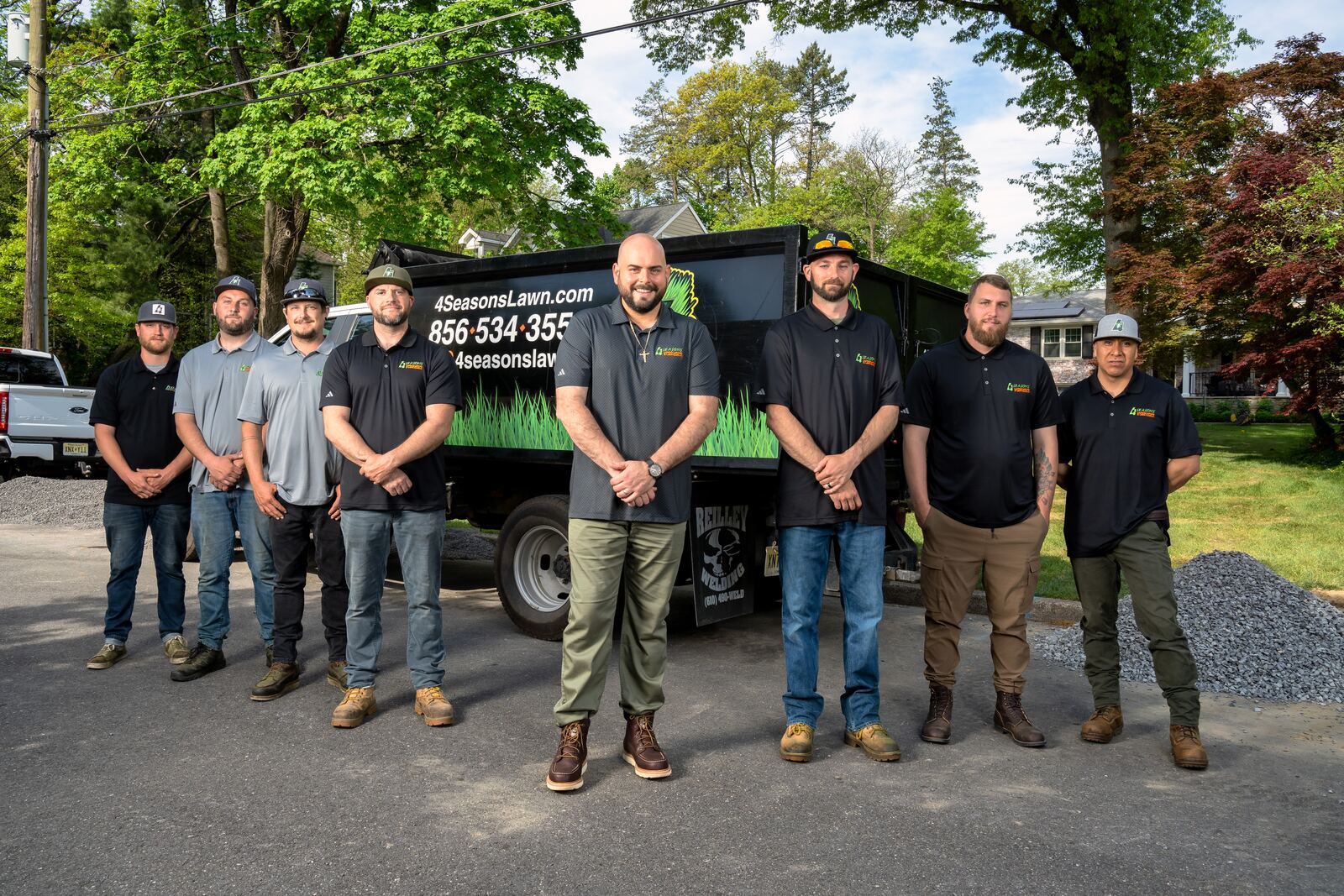 The 4 Seasons Lawns crew in branded uniforms in front of a company truck