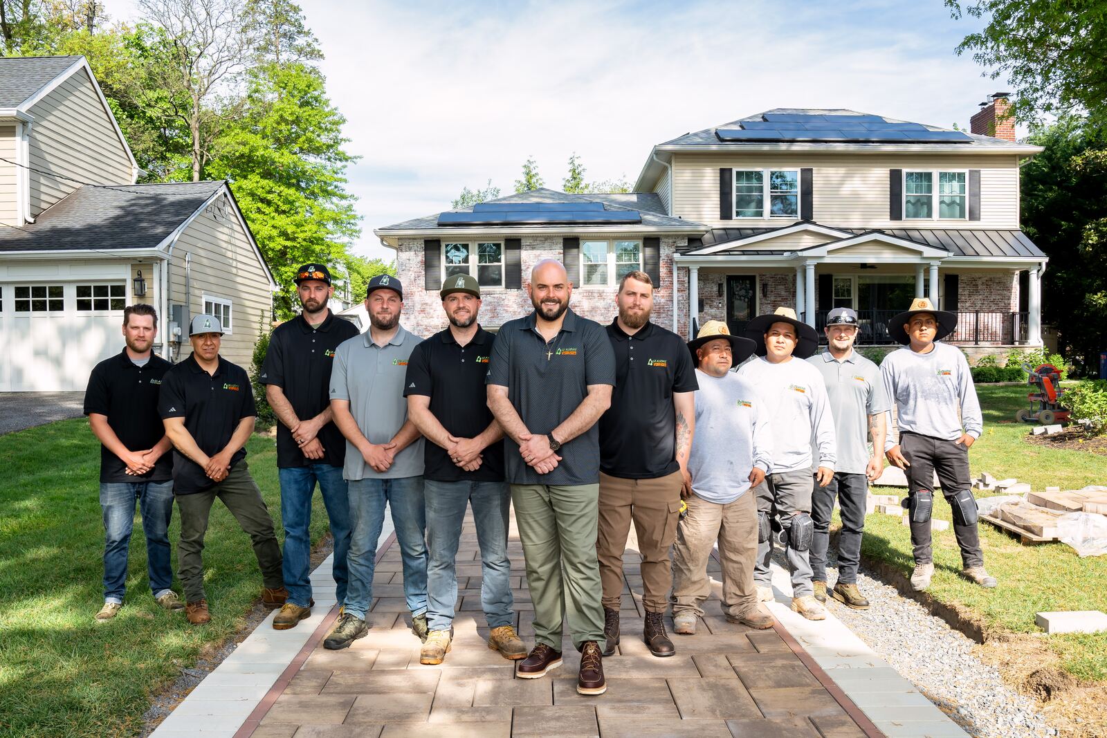 The 4 Seasons Lawns crew on a new paver walkway in front of a stone home