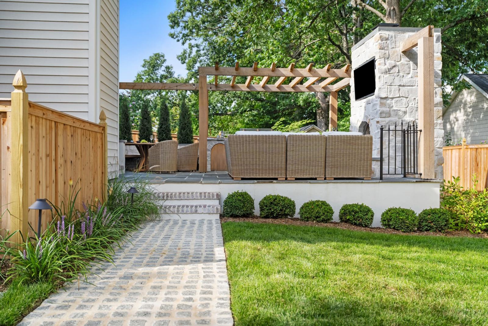 Backyard with stone fireplace, cedar pergola, paver walkway and fresh lawn