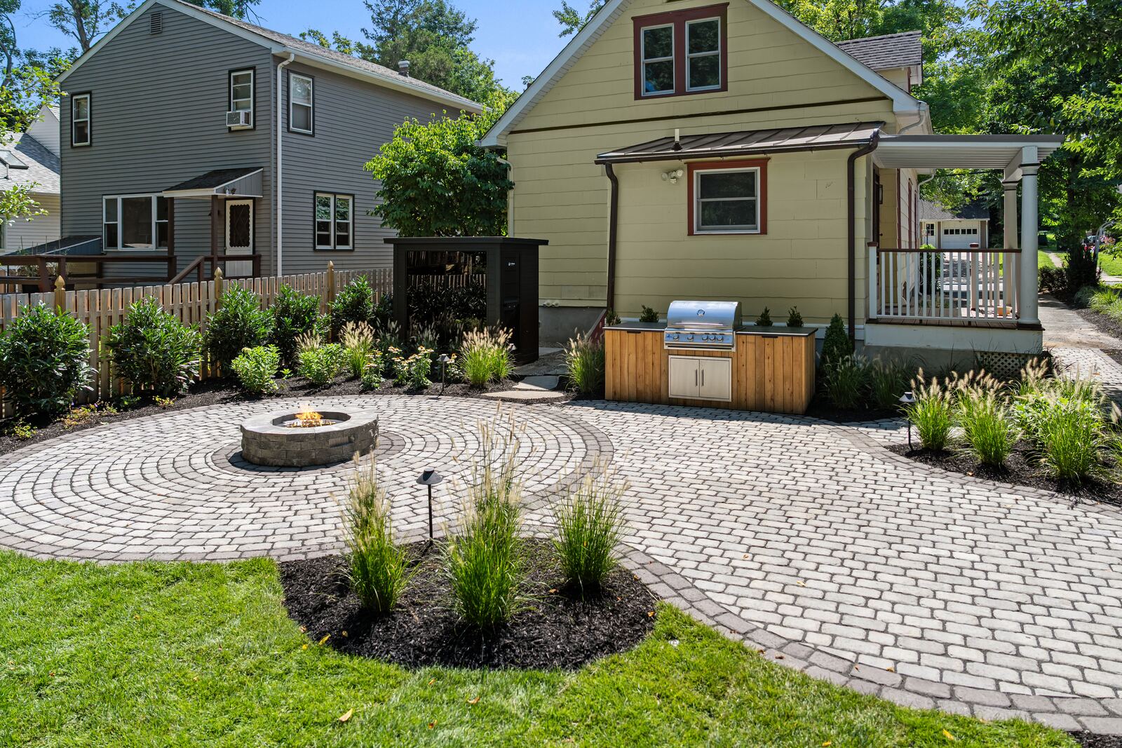 Circular paver patio with a stone fire pit, grill station and new planting beds