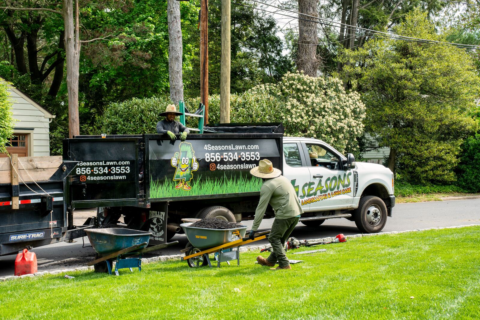 Crew moving mulch by wheelbarrow from a 4 Seasons truck onto a property