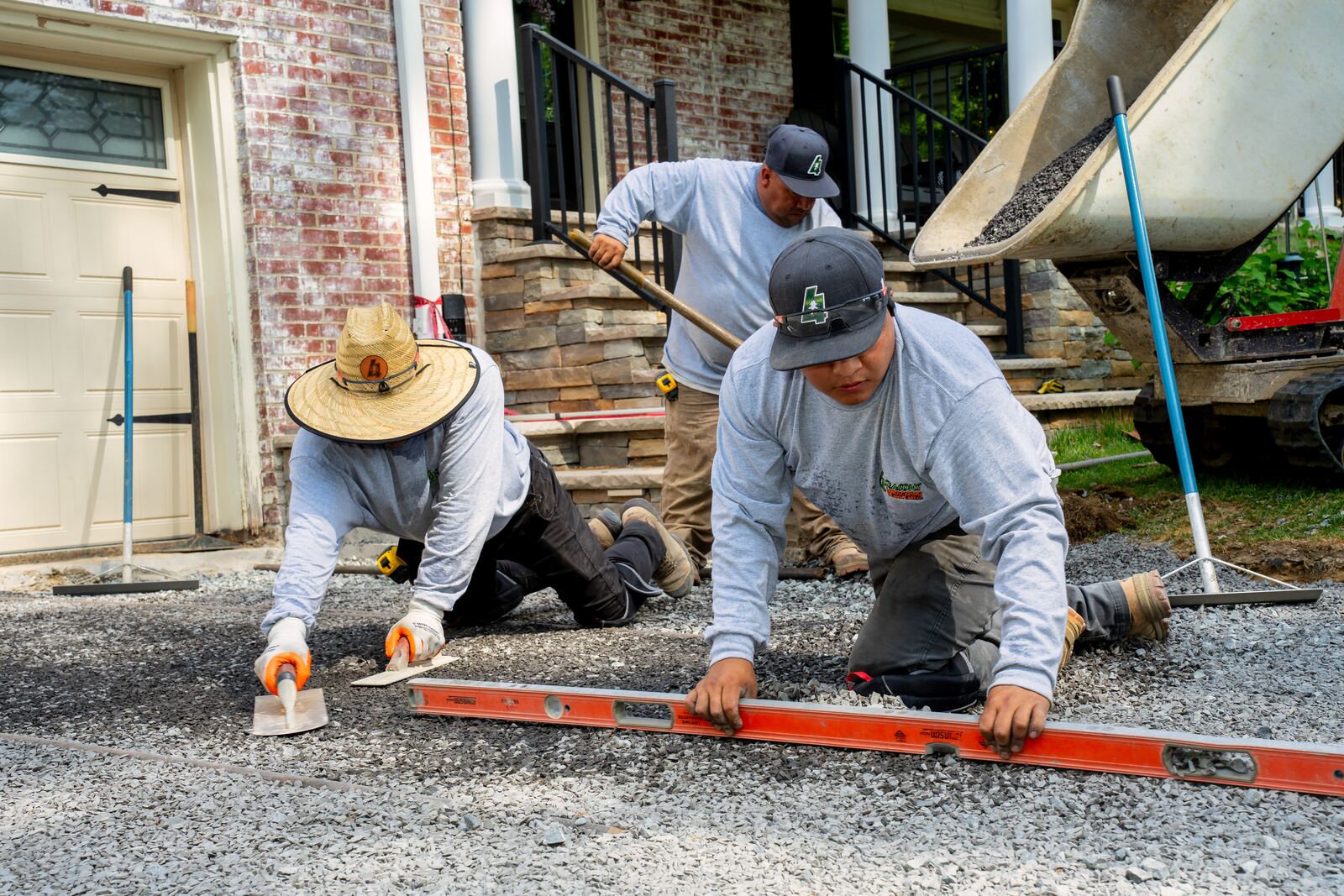 Crew checking a gravel base with a long level at a front entrance