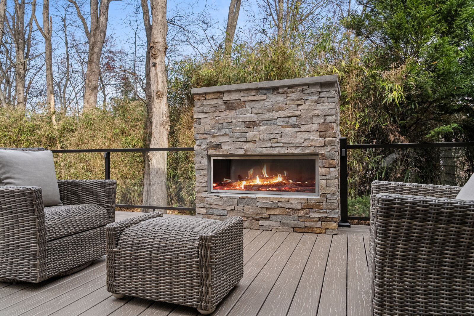 Stacked-stone fireplace on a composite deck with wicker lounge chairs