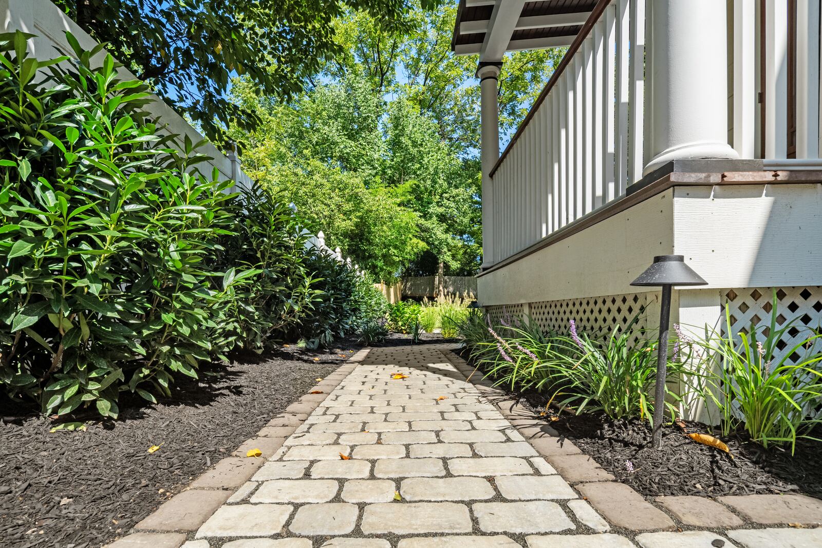 Tumbled-paver side walkway with path lights between planting beds